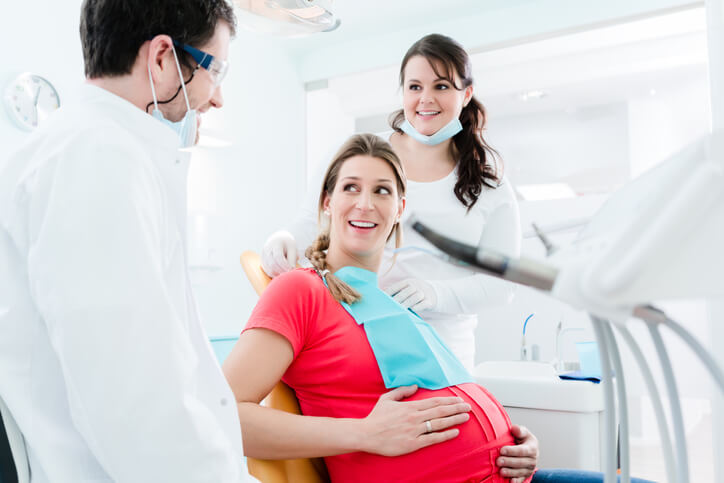 pregnancy dental care at beach grove dental - a young pregnant woman sitting on a dental chair and talking to her dentist