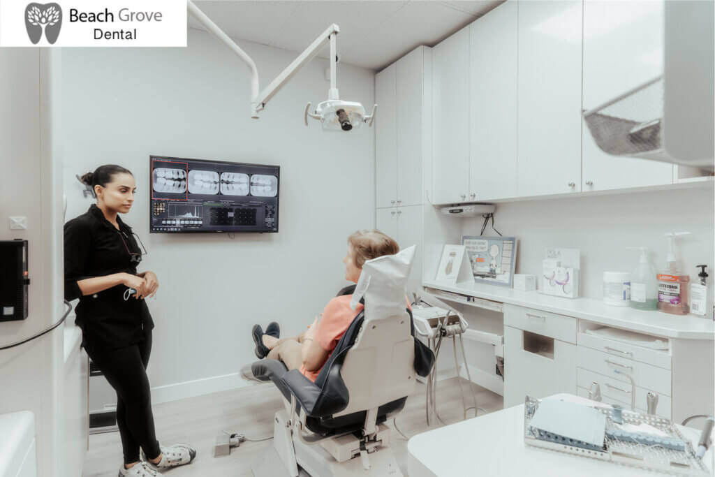 A patient sitting in a dental chair and a dentist at Beach Grove Dental having a discussion about the results of a dental checkup