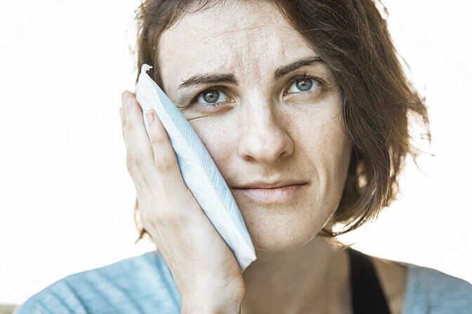 a woman needing an emergency dental appointment holding cloth to cheek